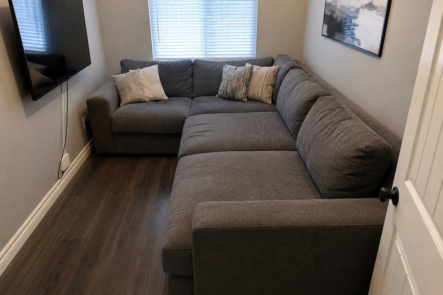  A large gray fabric sofa filling most of a small living room with little space left around it 