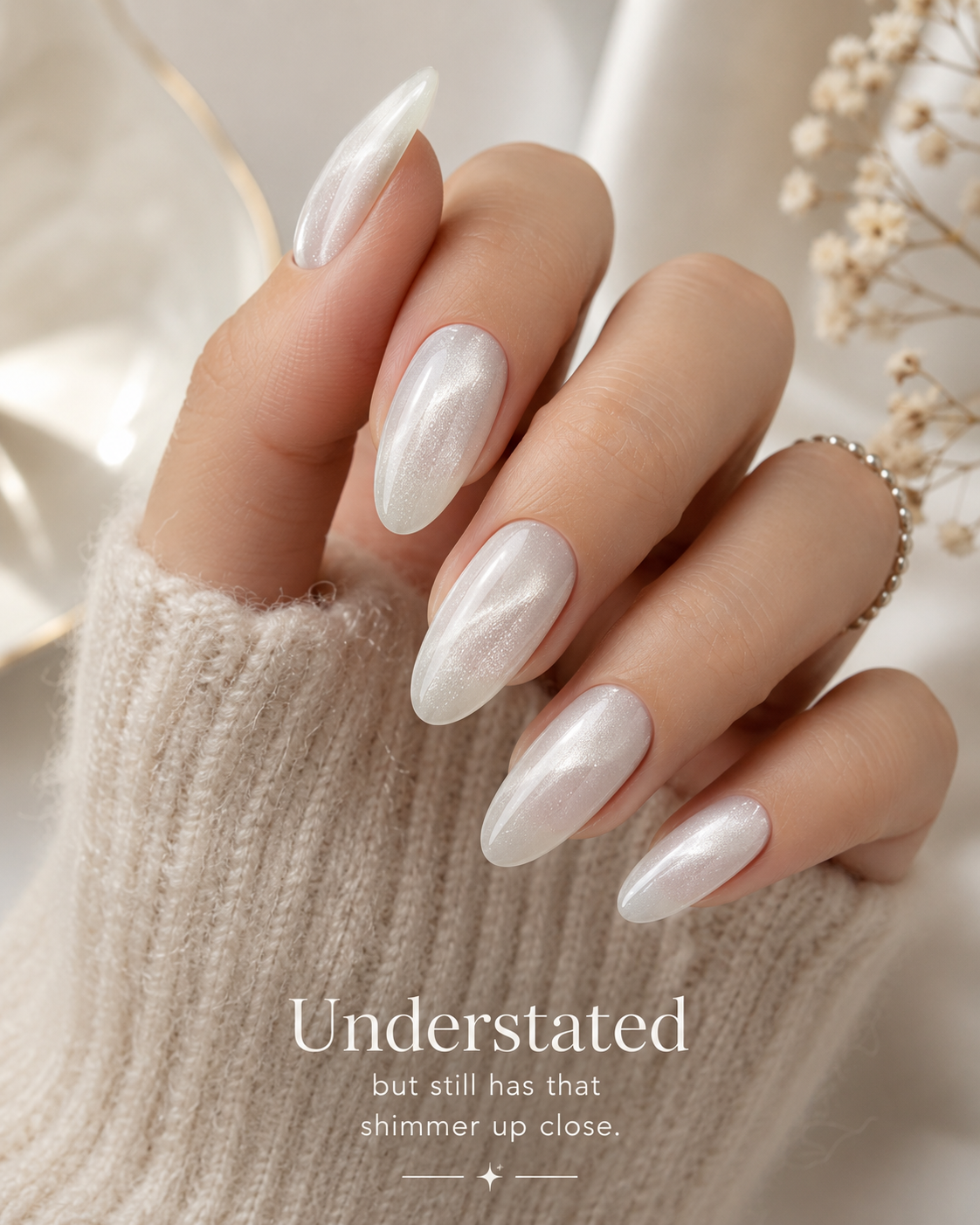 Milky white cat eye nails with a soft magnetic shimmer on long almond-shaped nails.